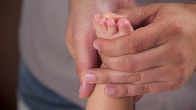 The masseur gives a massage to the baby. The masseur's hands are kneading the baby's feet. Massage for children relieving tone. close-up
