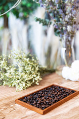 Roasted coffee beans in  behind beautiful flower background.