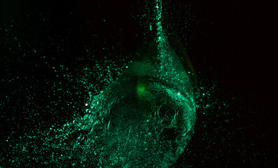 Splashes waterballoon bursting against black background and in a galaxy of water drops closeups