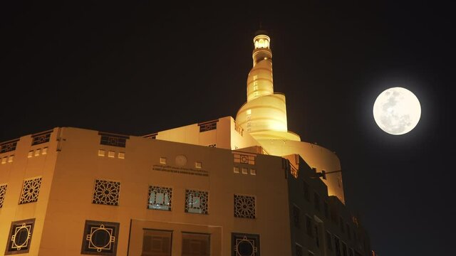 Night view of Spiral Mosque in Doha, Qatar. Beautiful light on the Abdulla Bin Zaid Al Mahmoud Islamic Cultural Center in summer night with a big shining moon. Famous Islamic landmark Fanar.