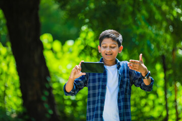 childhood, technology and people concept - indian cute school boy showing smartphone with blank screen