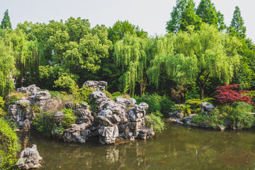 Fototapeta na wymiar Rocks in pond surrounded by trees in Shenyuan (Shen Garden) scenic area in Shaoxing, China