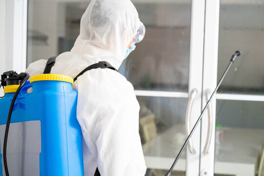 health care worker in white jumpsuit and protective face mask using spraying machine to disinfect virus pandemic. Health care and midicine concept. New normal social distancing concept.