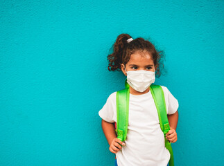 Cute little girl with backpack while wearing surgical face mask for coronavirus - Portrait of child going back to school