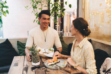 Cheerful diverse couple sitting in cafe while having lunch together
