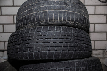 Obraz premium Used car tires against a brick wall. Worn tread of summer tires 