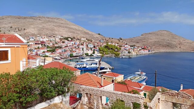 Rhodes, Greece: Pan shot of traditional colorful houses located on a steep hill on halki / chalki island on aegean sea coast