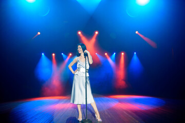 Bright stage lighting. Vocalist singing to microphone.