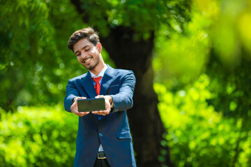 Happy businessman pointing finger on blank smartphone screen