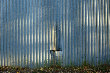 Corrugated metal fence with a dent and a ragged hole