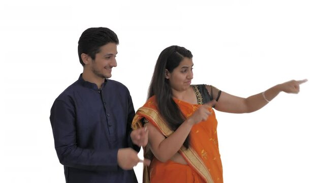 Young Indian couple pointing to the right side with approval. Common Indian body language. Isolated on white background