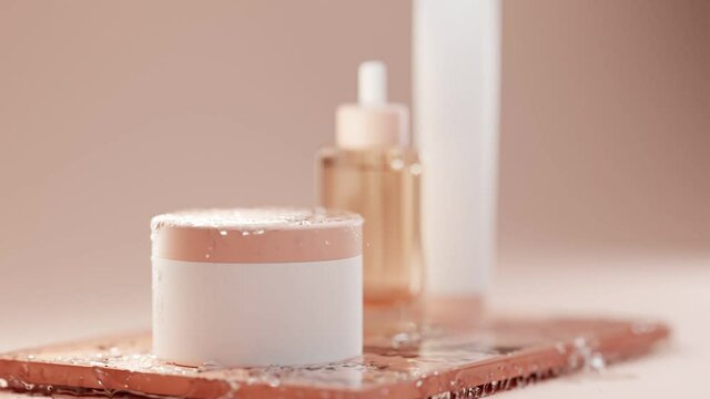 Set of cosmetic products for face and body skin. Glass bottle with pipette for serum and plastic jars with tuba on brown glossy table. Empty white packages on beige background in an icy water spray
