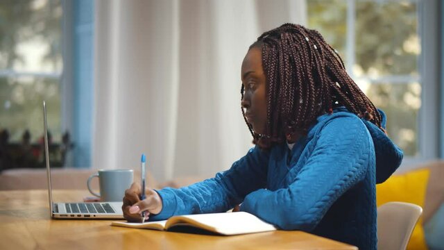 Young african female student sitting at table, using laptop when studying
