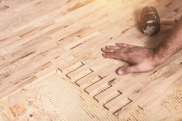 Carpenter on work laying laminate or parquet flooring installation of parquet. Pad applied with...