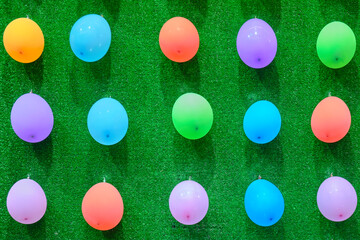 Different color balloons attached to the green background