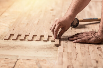 Worker installing wood parquet. Carpenter on work laying laminate or parquet flooring. installation of parquet. Home renovation, Close up