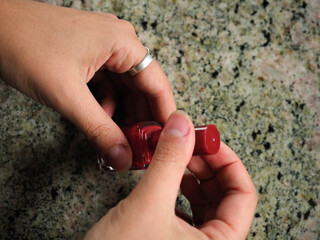 Hand of a young woman painting her red nails