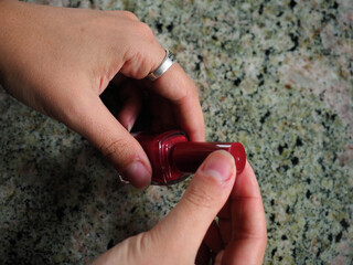 Hand of a young woman painting her red nails