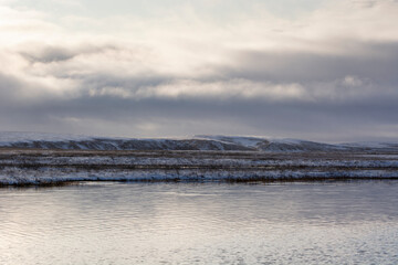 autumn landscape with a lake in the tundra on the background of snow clouds