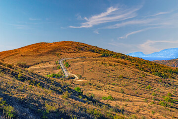 Landscape of the Crimean mountains, on a bright Sunny day, covered with small bushes, with a highway passing through it