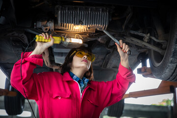 Fototapeta Young Female technician using lighting check underbody of car obraz