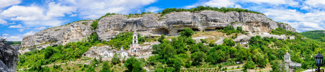 Fototapeta na wymiar Panoramic picture. Sheer cliffs of the plateau Burunchak. The Maryam-Dere gorge. Territory of the Holy Dormition Monastery near Bakhchisaray. Republic of Crimea.