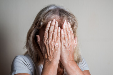 Contrast photography of mature woman covering her face dealing with the problem and showing his...