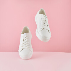 Pair of fashion stylish white sneakers, Running sports shoes on pastel pink background.