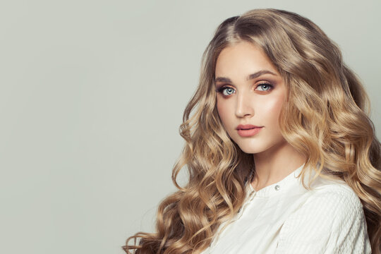 Beautiful young blonde woman fashion model with long healthy curly hairstyle