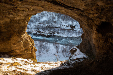 cave next to river in winter landscape