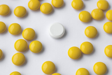 The pills are yellow scattered and one white pill is in the center.