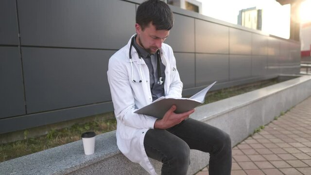 Tired overworked doctor reading medical report. Stressed doctor. Exhausted doctor resting after read medical records. Medicine concept. Tired medical physician in white coat hold folder with document
