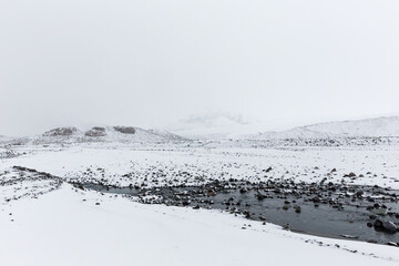 Snow covered mountains and blue river in Icelandic highlands