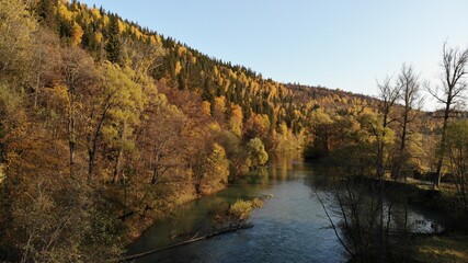 Beautiful autumn landscape. The river flows through the hills. Colored leaves on the trees. Autumn in Russia.