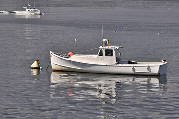White lobster boat anchored in harbor at Spruce Head Island, Maine; another boat entering harbor....
