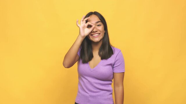 Young mixed race indian woman excited keeping ok gesture on eye