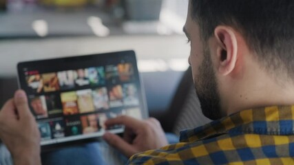 Young white man lying down on sofa in living room at home searching for on line films or TV series to watch for fun. Latino people choosing for movies on internet streaming service - Powered by Adobe