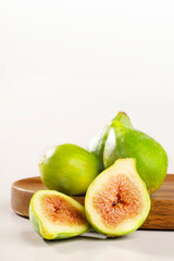 Three figs and one in half on white and wooden background