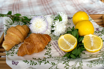 wooden tray with croissants and lemon on picnic