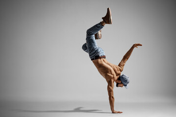 Shirtless man in jeans doing a handstand