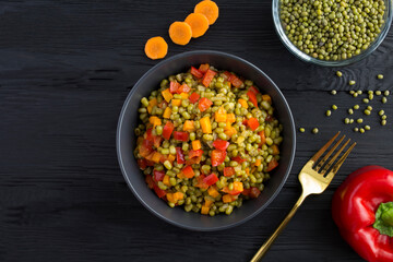 Top view of mung beans with vegetables in the bowl on  black wooden the  background with copy space