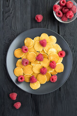 Top view of mini pancakes with raspberries  in the black plate on the dark  background. Location vertical.