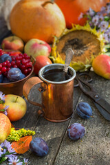 Naklejka na ściany i meble Copper mug with tea against the background of the autumn harvest of pumpkins, apples, plums, pears and viburnum on a wooden table. Vintage rustic style