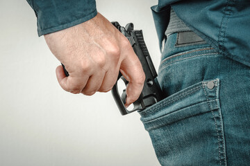 Man pulling his automatic gun out of jean pocket. Concealed pistol concept.