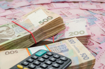 packs of hryvnia and a calculator. Ukrainian money 500 and 200 hryvnia. Financial concept. Lots of banknotes.