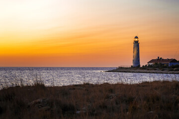 Romantic view of the lighthouse from the cliff at sunset