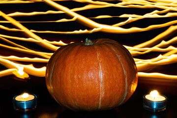 Orange pumpkin and two lighted tea candles on background of fire lines. Halloween concept
