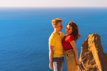 Fototapeta na wymiar Happy young couple man and woman embrace on the edge of a cliff on the Cape, family youth travel concept