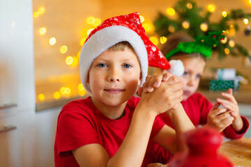Happy children are preparing gingerbread on the eve of new year. Boy and girl in the kitchen waiting for Christmas. Children make holiday cookies at home. Family traditions on Christmas Eve