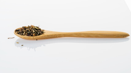 Heap of dried natural basil aromatic herbs on bamboo spoon.